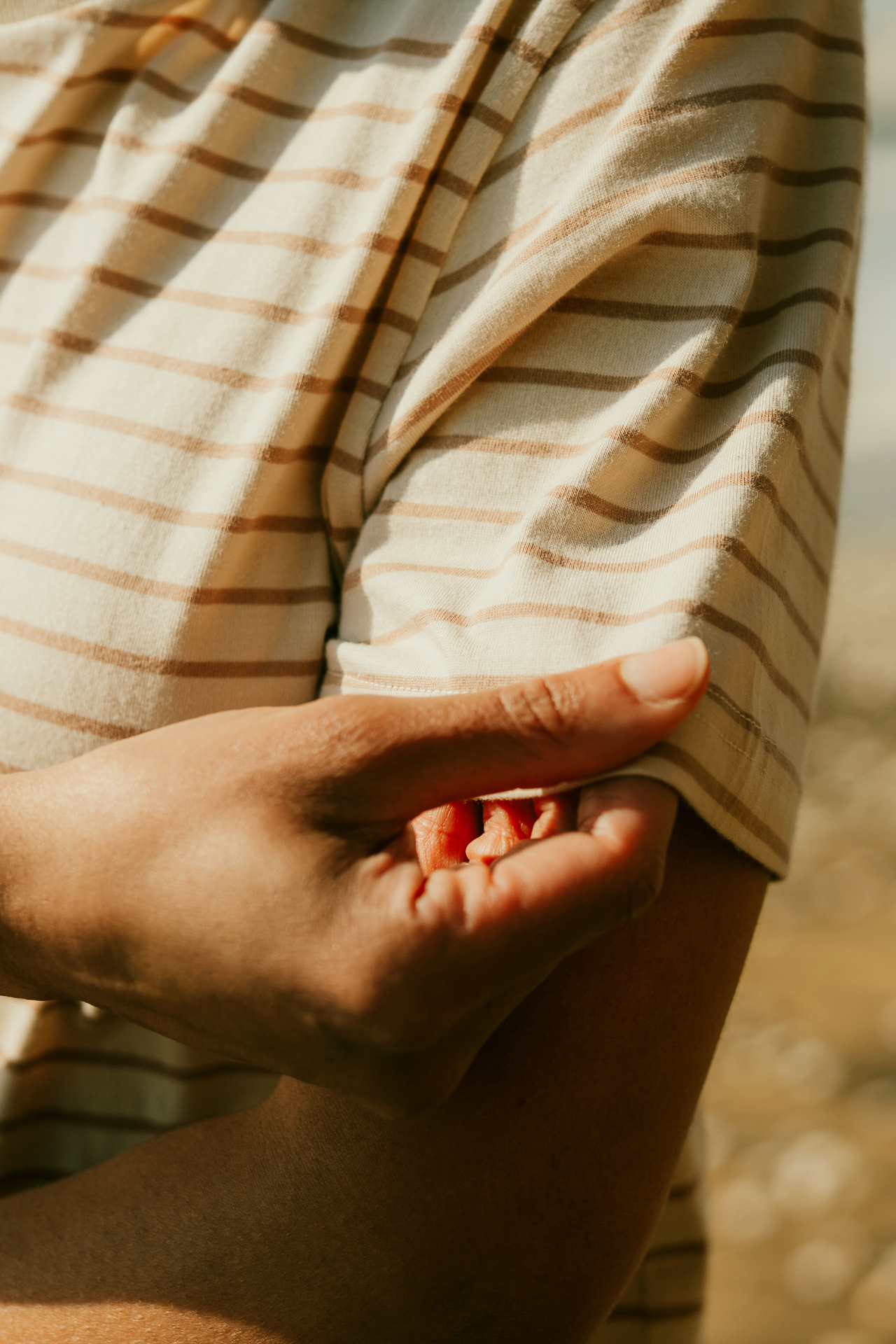 Person tugging the sleeve of a striped shirt