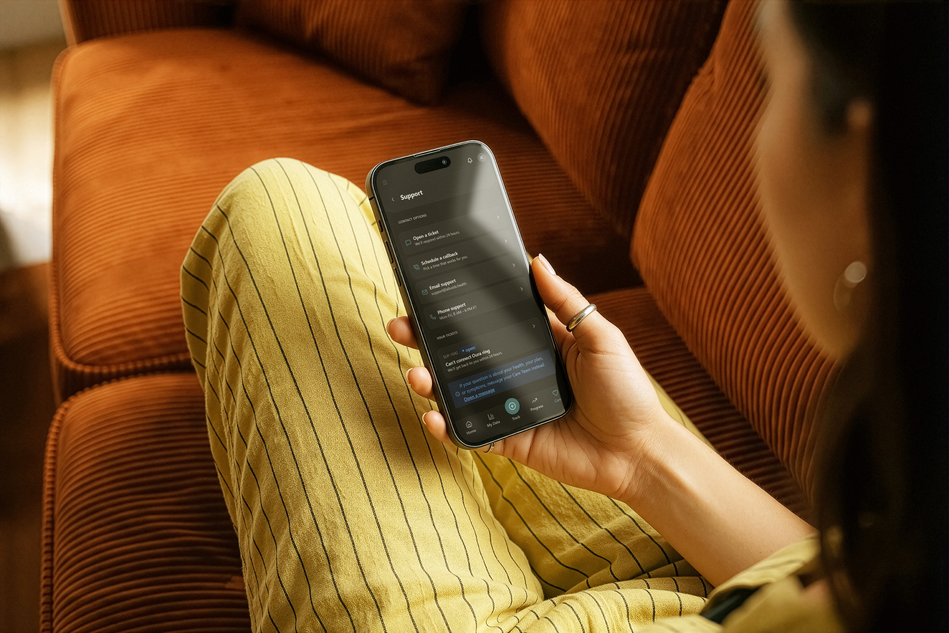 Woman holding a phone showing a member support chat interface