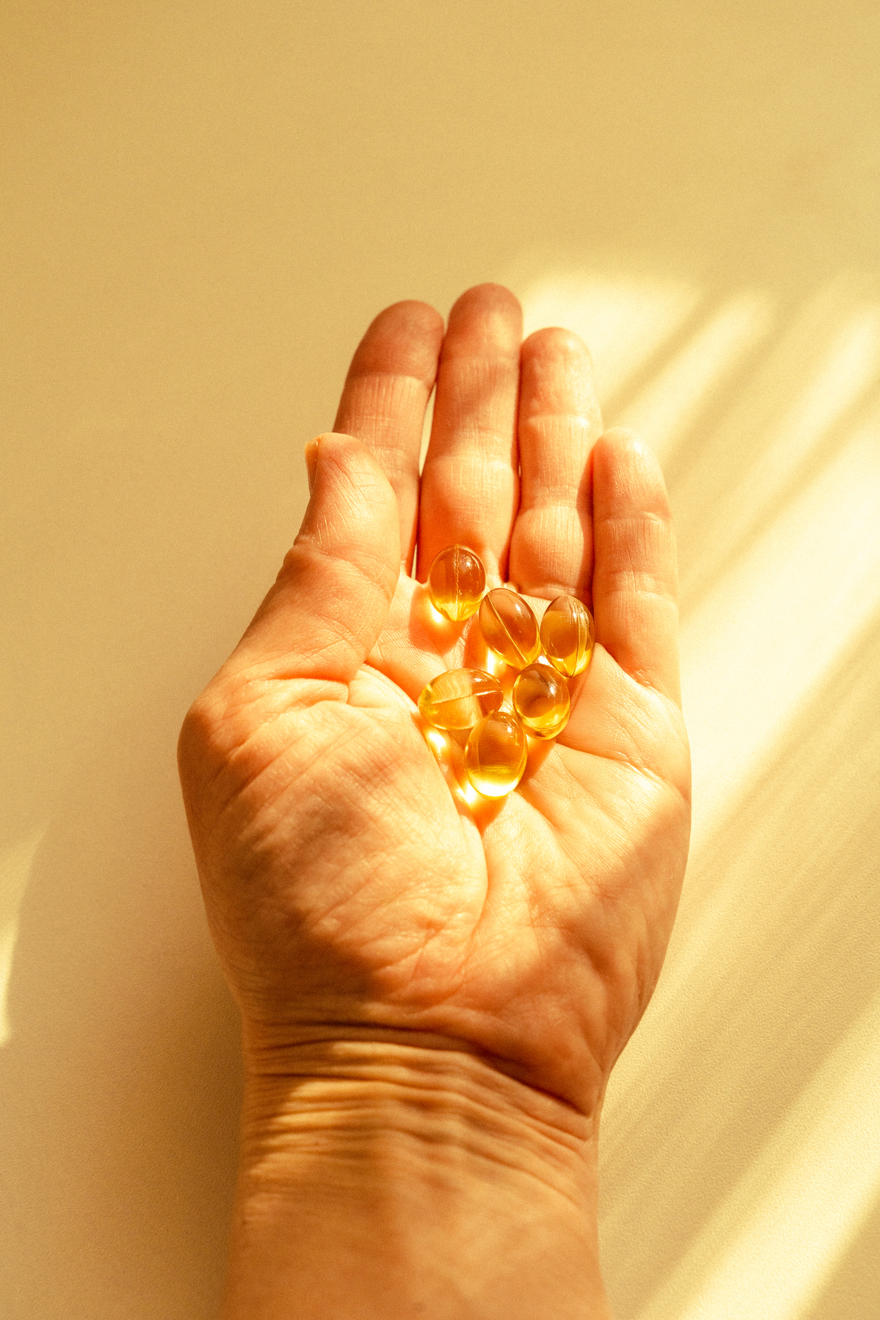 Hands cupping six wellness supplements in warm sunlight